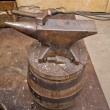 a blacksmith anvil and cross peen hammer sitting on a wooden barrel