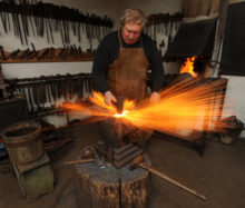 a blacksmith working on a piece of metal with sparks flying